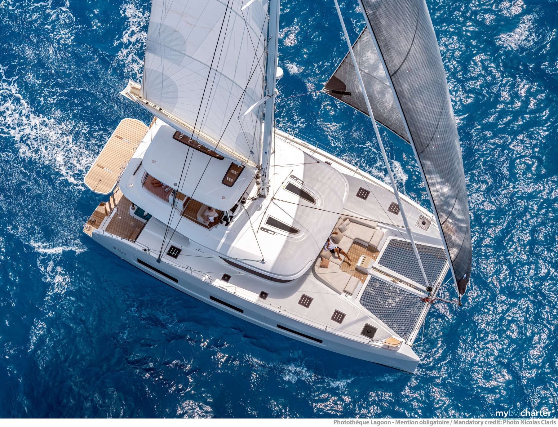 Seven Seas, a white sailing catamaran, seen from above in brilliant blue water
